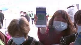 Passengers from Wuhan show QR code for checks upon arrival at airport