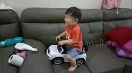 Funny toddler riding push car on sofa