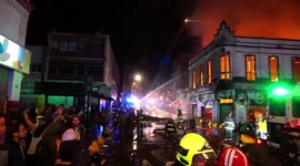 People upset with special forces, shout insults at them while an old building from 1912 is on fire after protests in Chile