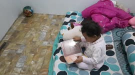 A 2-year-old girl reads a book in a language that is not understood