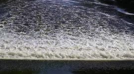 Satisfying slow-motion water flowing over a weir in the River Aire in UK