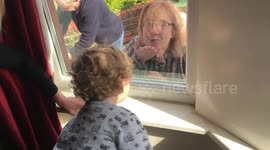 Grandparents communicate with grandson through closed window due to social distancing