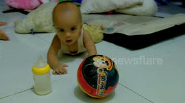 Baby boy learning to crawl and playing with ball