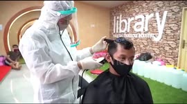 Indonesian care workers wear protective gear while taking turns to cut each other's hair during COVID-19 pandemic