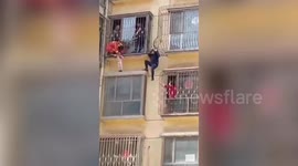 Firefighters and police officers in China rescue child hanging out of third-floor window