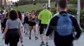 people out along the beach promenade for the first day of exercise after 7 weeks of lockdown in barcelona, spain