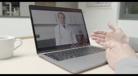 Online video call via laptop of male doctor in white lab coat consulting sick man talking at kitchen table. Medicine, healthcare, Technology