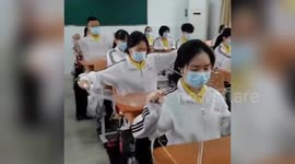 Chinese students dine in their classroom with transparent boards surrounding their desks