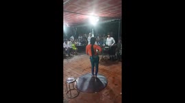 The woman demonstrating the skill of using her head to pour water from a bottle into the cups