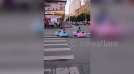Woman drives toy car with son sitting inside on Chinese road