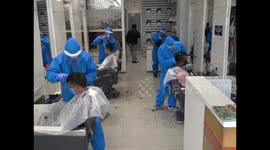 Barbers in western India wear protective gear while cutting hair