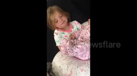 Newsflare Edit - Girl holds her new baby sister and the makes her smile