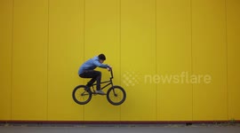 Cool BMX Bike professional Athlete performs jumps next to yellow wall