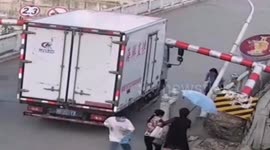 Chinese woman narrowly escapes being hit by height restriction barrier after truck knocks it down