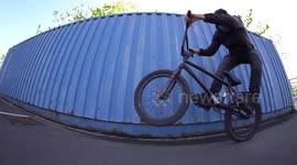 Young BMX Bike professional Athlete performs wheelie tricks on his BMX Bike / Blue Wall Visual