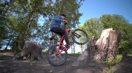 Cool MTB Bike professional Athlete performs wheelie tricks on his Bike on a tree / Action - Extreme - Fun Sports