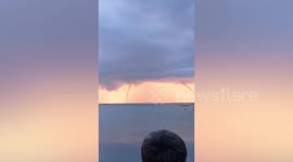 Triple waterspout forms in front of beautiful pink sunset