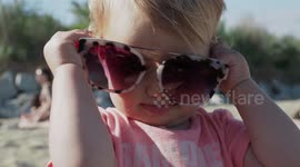 Cute Baby Girl Tries to Put on Her Mummy’s Sunglasses on the Beach