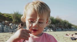 Cute Baby Girl Tries to Put on Her Mummy’s Sunglasses on the Beach