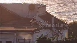 House left half dangling over collapsed cliff at sunset, Eastchurch, UK
