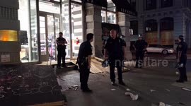 New York police officers stand guard in front of looted shops after curfew is announced
