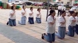 Chinese employees kneel down and chant slogans to give thanks to their company