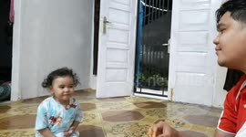 The toddler jokes while eating with his father