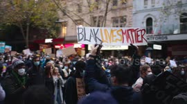 Young black BLM protestors holding signs, Melbourne
