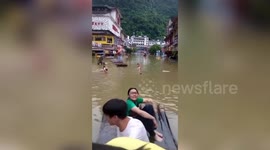 Chinese residents float on bamboo rafts to avoid flash floods at submerged tourist attraction
