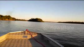 Sailing across a wide river during sunset.
