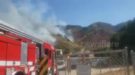 Firefighters battle wildfire burning through Southern Californian hillside