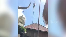 Indonesian man climbs up satellite dish pole to get kite tangled on it
