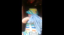 4 months old baby trying to get his sun hat off in the buggy