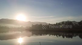 Videographer captures pretty scene as sun rises behind hills, rivers and bridges in Indonesia's Padang