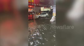 Motorists battle through flooded road after summer rain storm in Thailand