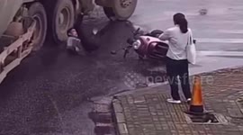 Chinese scooter rider narrowly avoids being run over by truck after falling in front of it