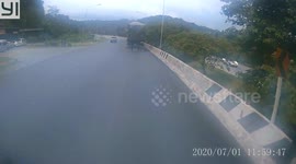 Motorcycle rider takes a short cut across road but is almost hit by oncoming lorry