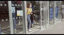 Young woman leaving supermarket in city wearing protective face mask during Covid 19 pandemic