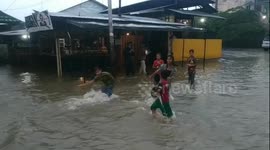 Groups of children swim in flooded road in Indonesia