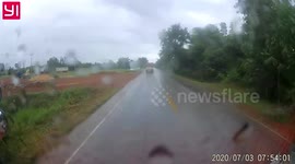 Overtaking driver narrowly avoids head-on crash on wet slippery road in Thailand