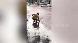 Deliveryman cleans street drains barehanded in China during heavy rain