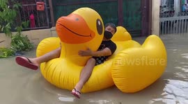 Residents in Thailand use inflatable rubber duck to ride to the shops after rain flooded roads