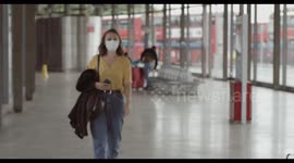 Female in airport bus terminal wearing protective face mask using smart phone during covid19 pandemic