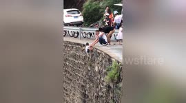 Man dangerously hangs child off cliff to take photos in north China