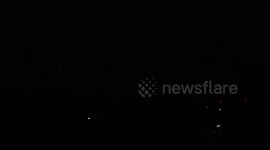 An airplane flies across a sky with a raging electrical storm.