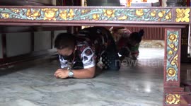 Buddhist followers crawl under ancient wooden bed for good luck in Thailand