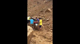 People try to move across the road buried by rocks and mud due to flash flood in northern Vietnam