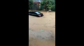 Residents look on as vehicles swept away by deep floodwater in Vietnam