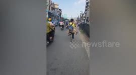 Mother rides with son on back of cycle using pieces of wood as seat