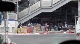 A snapshot of life on a busy Bangkok street, you can see construction workers and traffic, most people are wearing masks.
